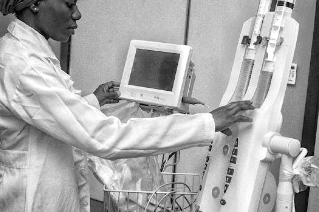 A focused healthcare worker operates advanced medical machinery in a clinical setting.