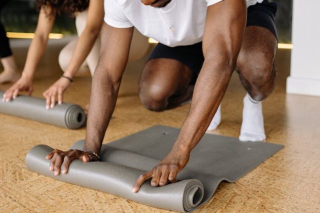 Diverse group of adults rolling yoga mats in a studio, preparing for exercise.